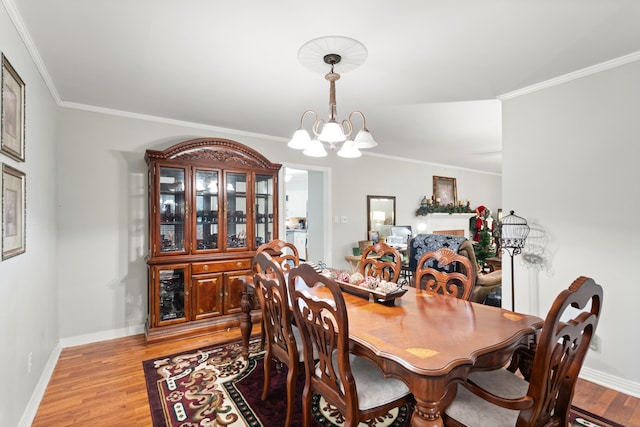 dining room with crown molding, light wood-type flooring, and a notable chandelier