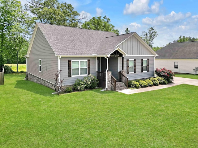 - view of front of house featuring a shingled roof, board and batten siding, and a front yard