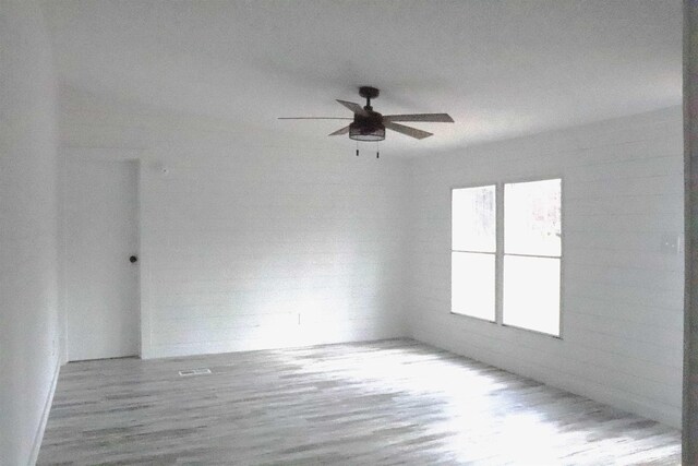  - spare room with wood finished floors, visible vents, and ceiling fan