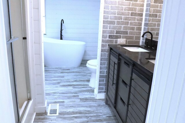  - full bathroom with vanity, wood finished floors, visible vents, a soaking tub, and toilet