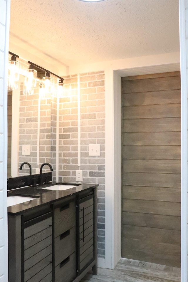  - bathroom featuring a sink, a textured ceiling, and double vanity