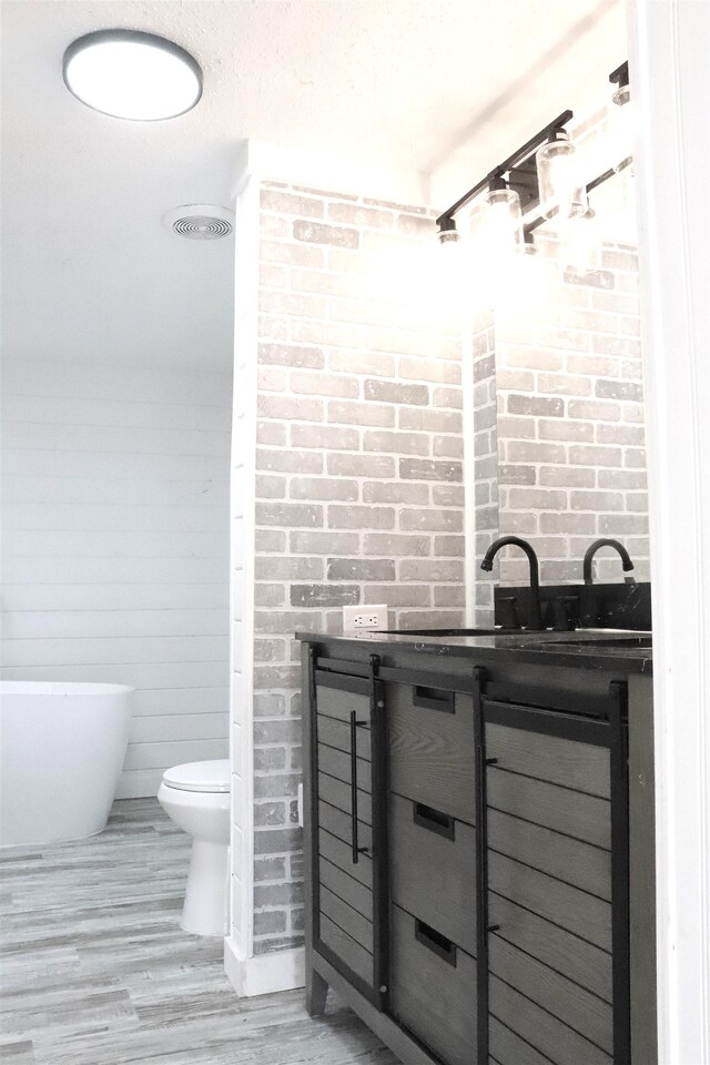  - bathroom with a freestanding tub, toilet, and brick wall