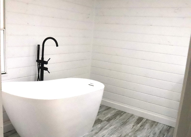  - bathroom featuring a freestanding tub, wooden walls, and wood finished floors