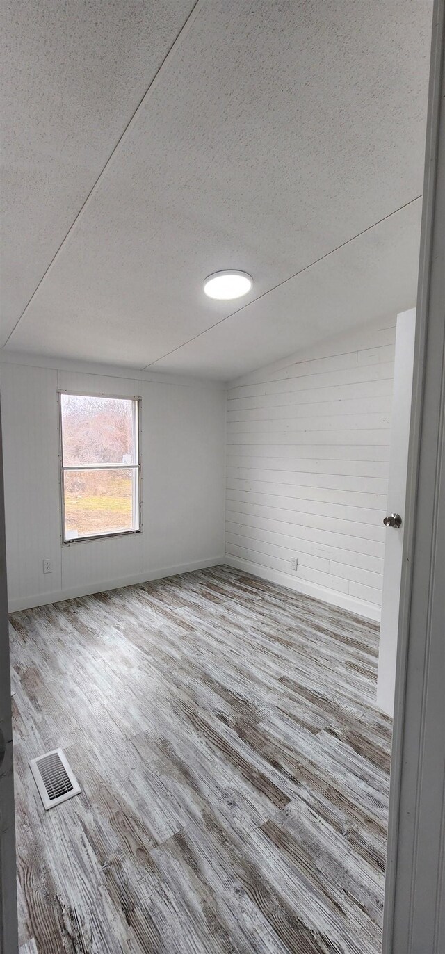  - empty room with wood finished floors, visible vents, and a textured ceiling