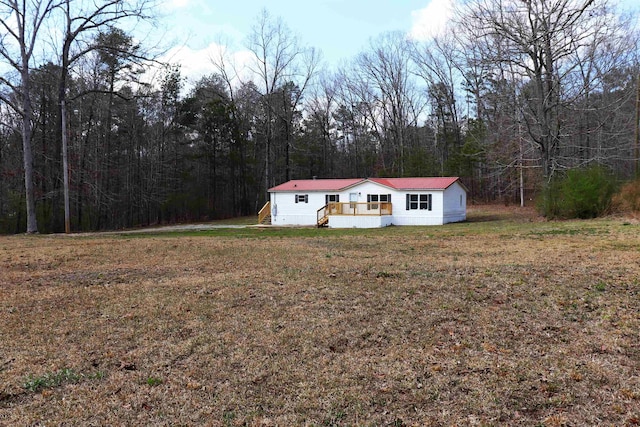 manufactured / mobile home with a view of trees, a front yard, and metal roof