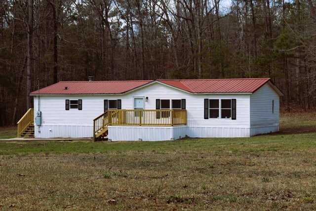  - manufactured / mobile home featuring metal roof, a front lawn, and a view of trees