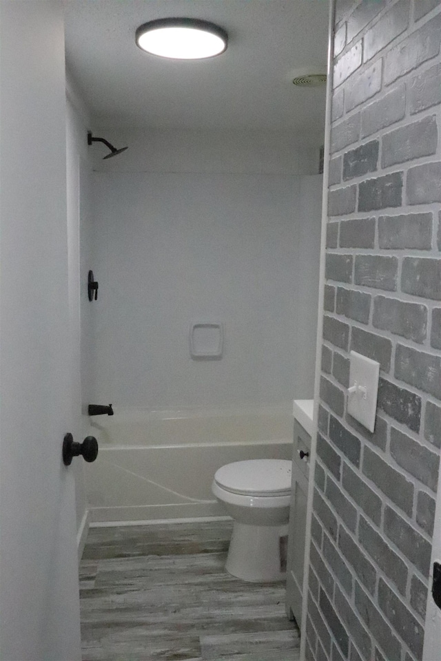  - bathroom with wood finished floors, toilet, and washtub / shower combination