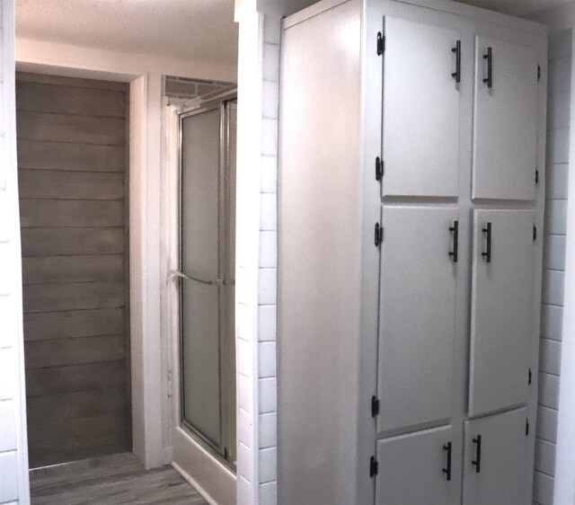  - bathroom with wood finished floors and a stall shower