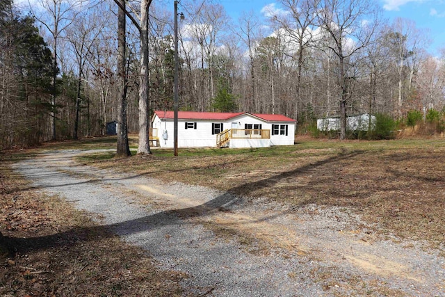 manufactured / mobile home featuring metal roof, a wooded view, and driveway