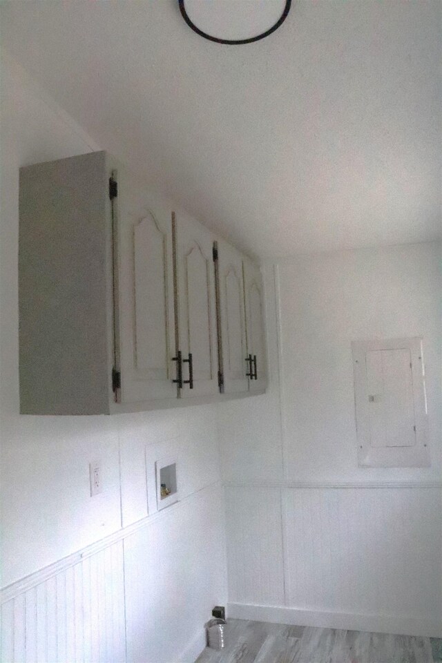  - laundry area with electric panel, laundry area, hookup for a washing machine, light wood-style flooring, and wainscoting