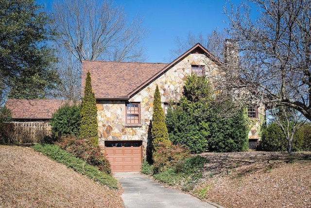 view of front of property with a garage, stone siding, driveway, and a chimney