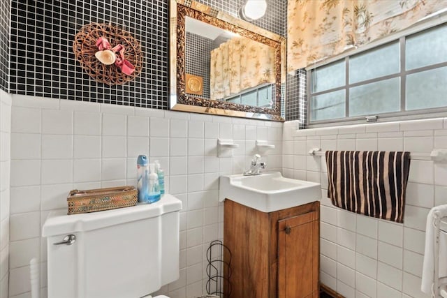 bathroom with vanity, toilet, and tile walls