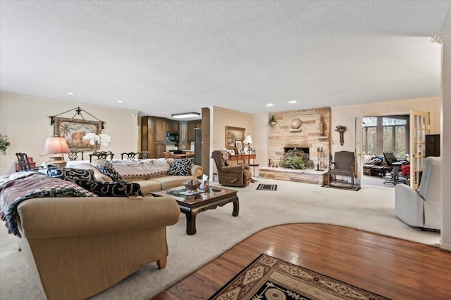 living room with hardwood / wood-style flooring, a large fireplace, and a textured ceiling