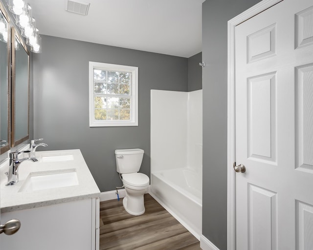  - bathroom with double vanity, toilet, baseboards, wood finished floors, and shower / bathtub combination