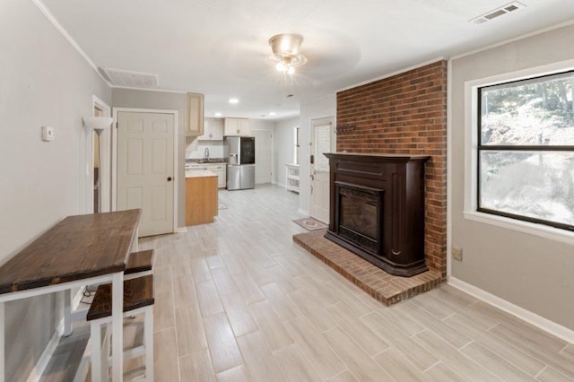 unfurnished living room with a fireplace, light hardwood / wood-style floors, ornamental molding, and sink