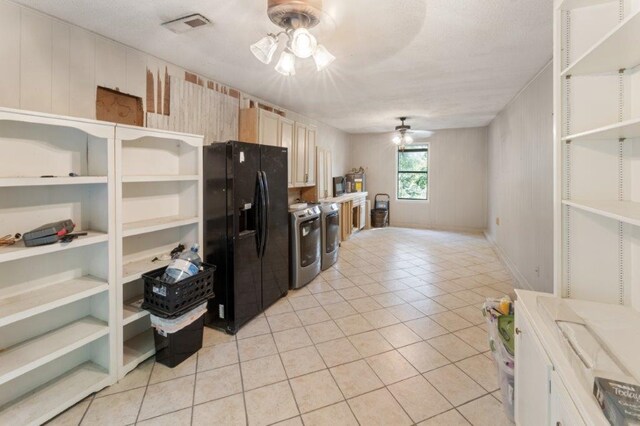 kitchen featuring washing machine and dryer, ceiling fan, black fridge with ice dispenser, and light tile patterned floors