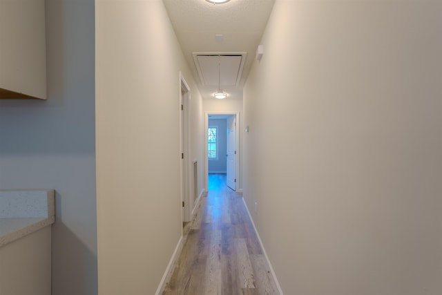 corridor featuring light hardwood / wood-style floors and a textured ceiling