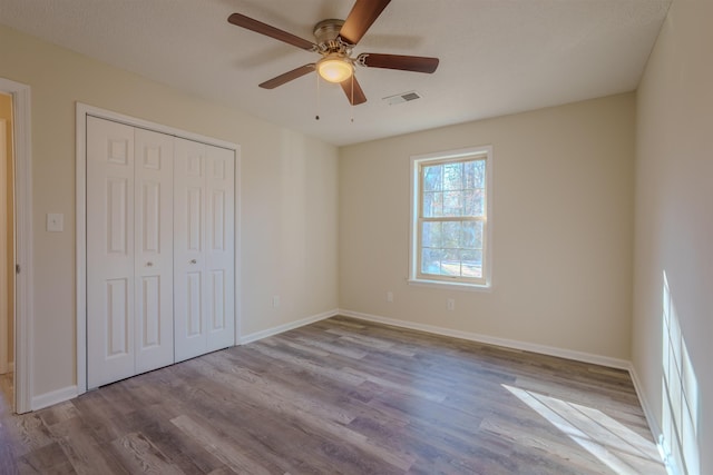 unfurnished bedroom featuring ceiling fan, a closet, and light hardwood / wood-style flooring