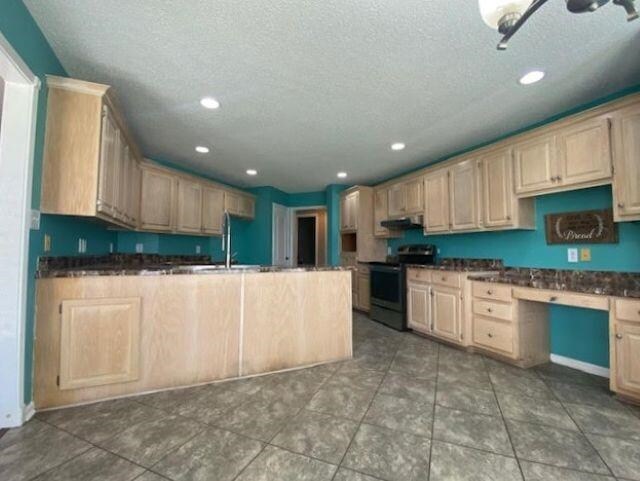  - kitchen featuring stainless steel electric range, dark countertops, a textured ceiling, a peninsula, and a sink