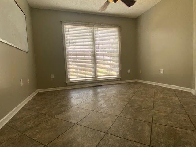  - unfurnished room with ceiling fan, dark tile patterned floors, and baseboards