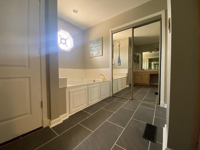  - full bath featuring a garden tub, a textured ceiling, and tile patterned floors