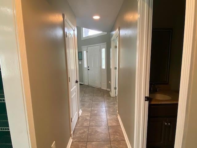  - hallway with light tile patterned floors, a sink, recessed lighting, and baseboards