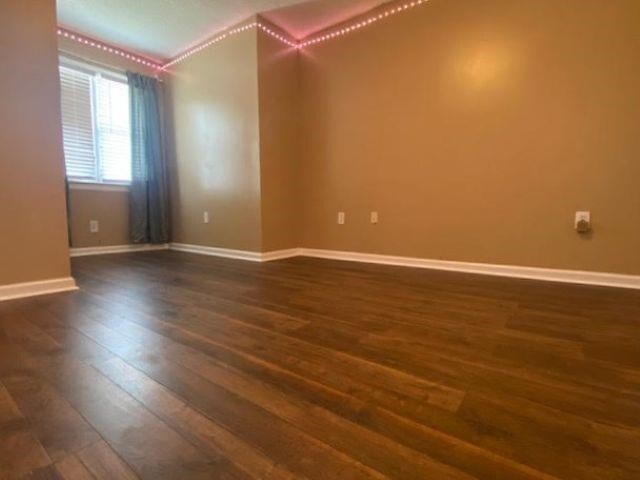  - unfurnished room featuring dark wood-style floors, baseboards, and ornamental molding