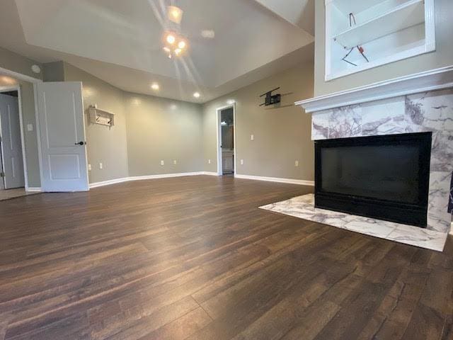  - unfurnished living room with wood finished floors, a premium fireplace, baseboards, lofted ceiling, and recessed lighting