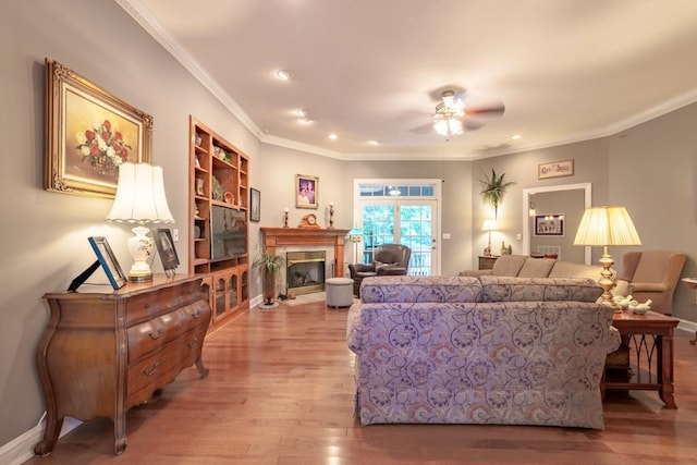 living room with wood-type flooring, ceiling fan, and crown molding