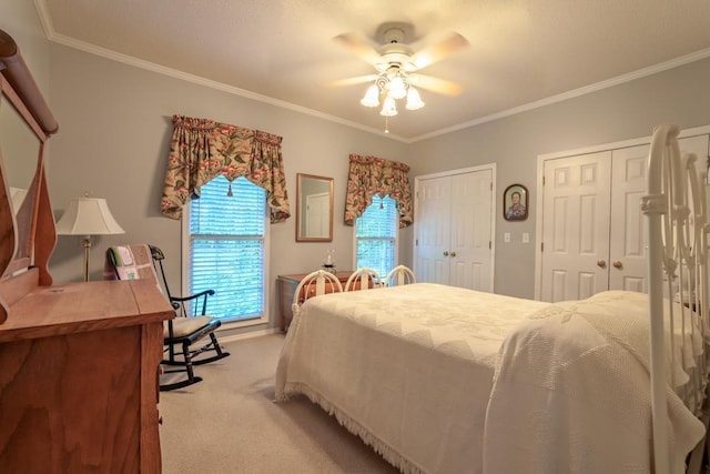 carpeted bedroom with ceiling fan, crown molding, and multiple closets