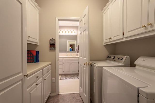 laundry area with washing machine and clothes dryer, sink, and cabinets