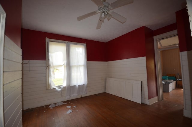 unfurnished room featuring ceiling fan, dark wood-type flooring, and wood walls