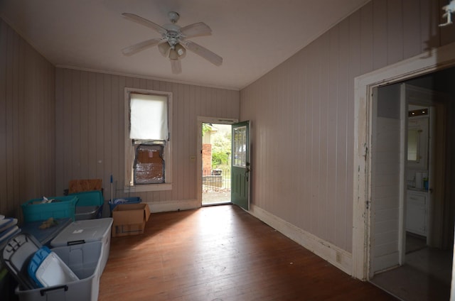 interior space featuring ceiling fan, wood-type flooring, and wood walls