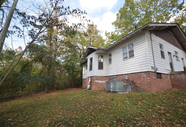 view of side of property with a yard and cooling unit