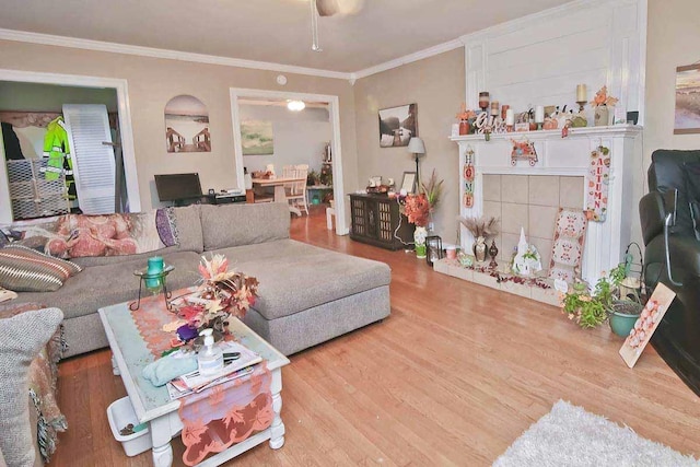 living room with hardwood / wood-style flooring, ceiling fan, and ornamental molding