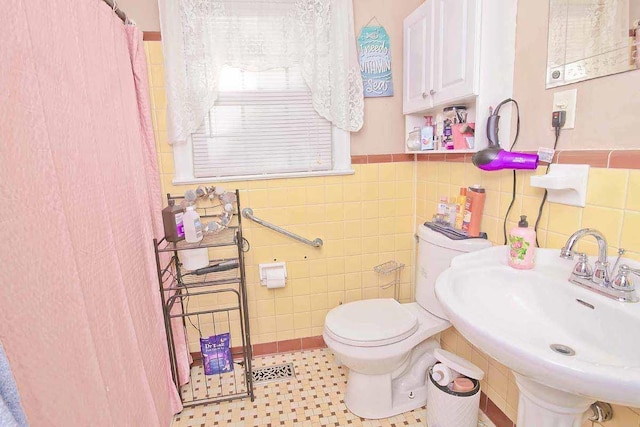 bathroom featuring toilet, tile walls, and sink