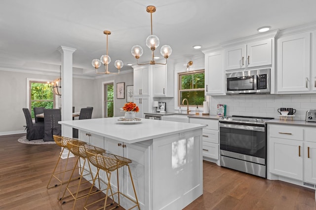 kitchen with stainless steel appliances, a sink, a chandelier, a center island, and a breakfast bar