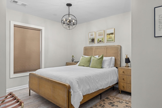bedroom featuring a chandelier, wood finished floors, and baseboards