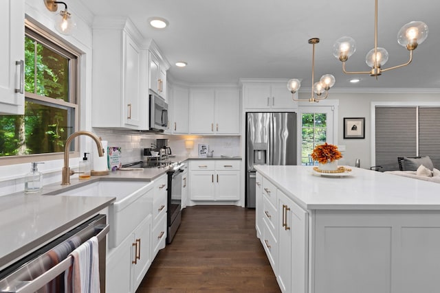 kitchen with stainless steel appliances, backsplash, white cabinetry, light countertops, and ornamental molding