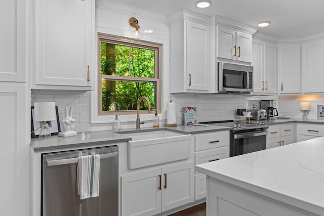 kitchen featuring appliances with stainless steel finishes, a sink, white cabinets, and backsplash