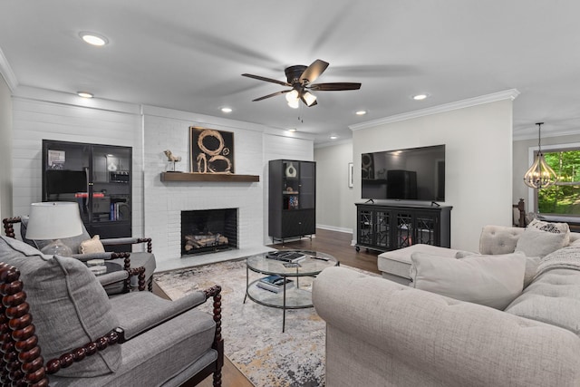 living area with crown molding, ceiling fan, wood finished floors, recessed lighting, and a brick fireplace
