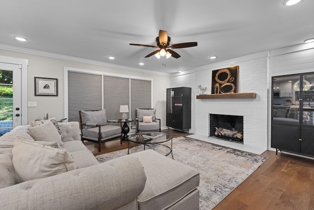 living room featuring a ceiling fan, crown molding, wood finished floors, a fireplace, and recessed lighting