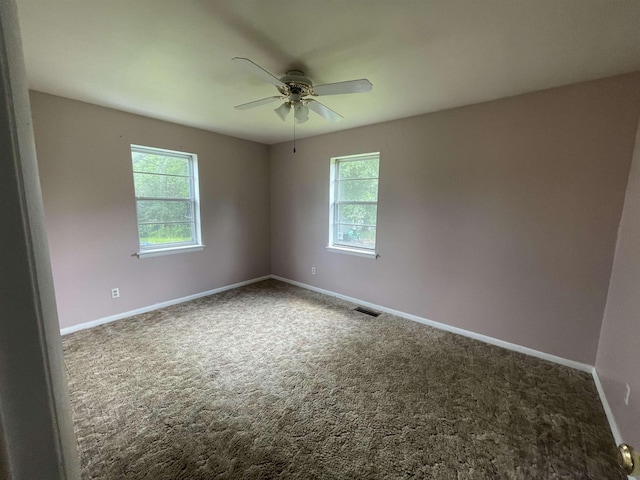  - carpeted spare room with healthy amount of natural light, a ceiling fan, and baseboards