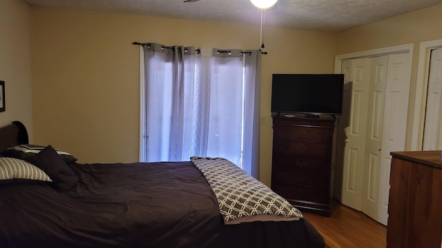 bedroom with ceiling fan, wood-type flooring, and a textured ceiling