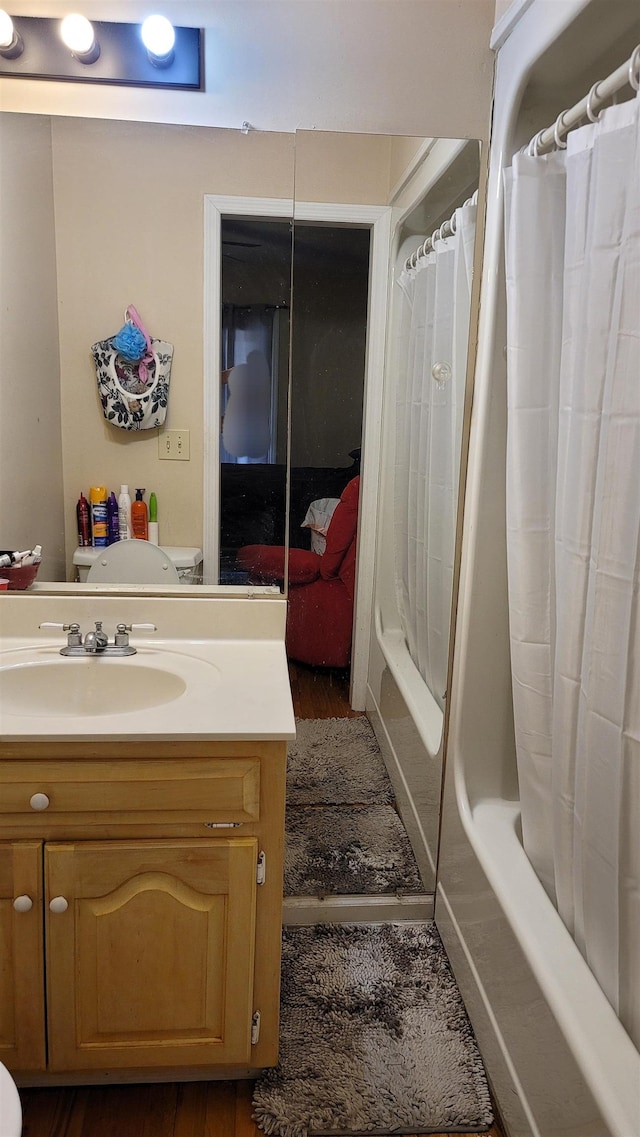 full bathroom featuring hardwood / wood-style floors, vanity, toilet, and shower / tub combo with curtain