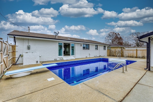 view of swimming pool with a diving board and a patio