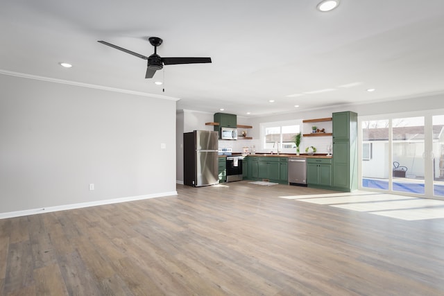 unfurnished living room featuring ceiling fan, ornamental molding, sink, and light wood-type flooring