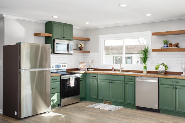 kitchen with sink, crown molding, appliances with stainless steel finishes, butcher block counters, and green cabinetry