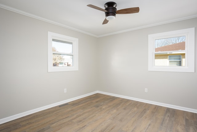 spare room featuring wood-type flooring, ornamental molding, a wealth of natural light, and ceiling fan