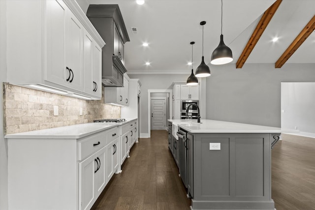 kitchen with stainless steel gas stovetop, a spacious island, hanging light fixtures, decorative backsplash, and beam ceiling